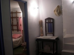 Rincón con mueble lavabo antiguo, espejo de madera y vista al dormitorio