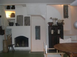 Comedor rústico con chimenea blanca, mesa redonda y alacena de madera oscura