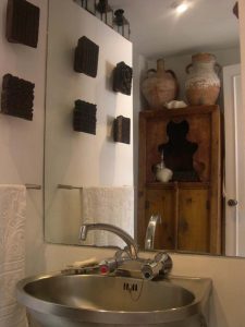 Lavabo de acero inoxidable frente a un espejo decorado con bloques de madera